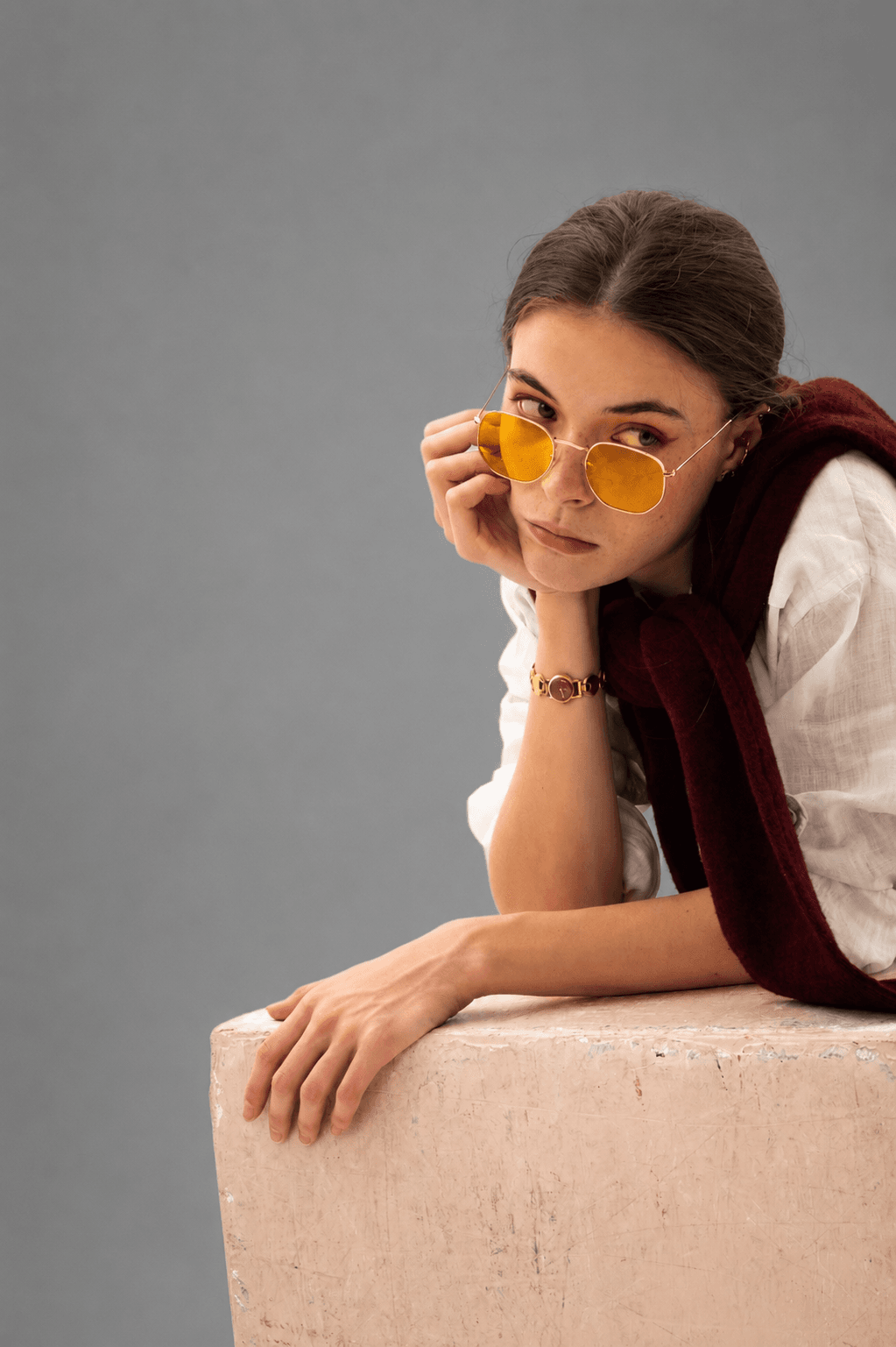 Portrait of a stylish young woman wearing luxury yellow sunglasses and a premium bracelet, showcasing elegant modern fashion accessories.